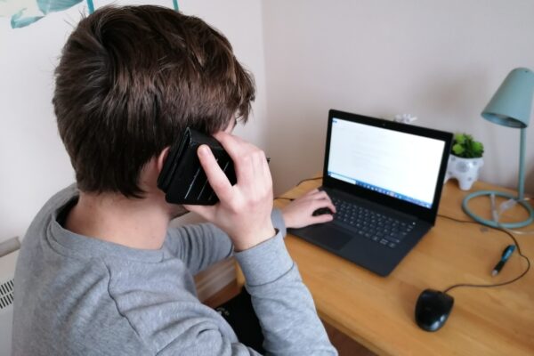 Working from home with phone to ear and laptop on desk