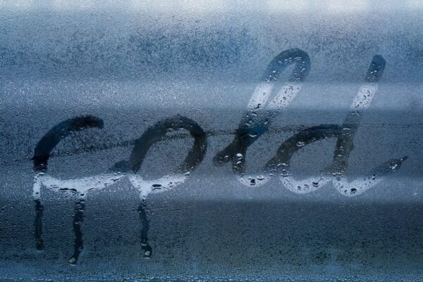 The word "cold" written on a window in condensation