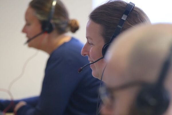 A close up image of three people wearing headsets working at tEC